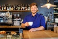 Handsome barista tasting a new type of coffee in his coffee shop