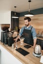Handsome barista grinds coffee beans in coffeemachine