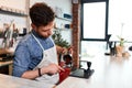 Handsome barman preparing ground coffee for customer