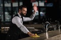 handsome bartender cleaning bar counter and waving hand