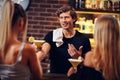 Handsome bartender serving cocktails in a pub