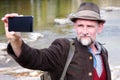 Bavarian man in his 50s standing by river and taking a selfie Royalty Free Stock Photo