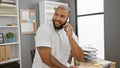 Handsome bearded african american man having a phone conversation in a modern office setting, casually dressed and engaging Royalty Free Stock Photo