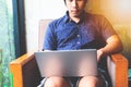 Handsome bearded Asian man working at cafe while sitting on the sofa.Concept of young people using laptop computer. Flare light Royalty Free Stock Photo