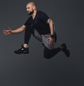 Handsome bearded athlete in sportswear jumping in a studio.