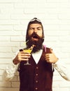 Handsome bearded aviator man with long beard and mustache on funny face holding glass of alcoholic cocktail in vintage Royalty Free Stock Photo