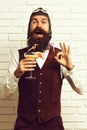 Handsome bearded aviator man with long beard and mustache on happy face holding glass of alcoholic cocktail in vintage Royalty Free Stock Photo