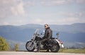 Bearded biker with long hair in black leather jacket and sunglasses sitting on modern motorcycle. Royalty Free Stock Photo