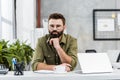 handsome bearded businessman resting chin on hand and looking at camera Royalty Free Stock Photo