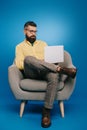 Handsome bearded businessman sitting in armchair with laptop Royalty Free Stock Photo