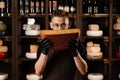 Handsome bearded cheese sommelier in fashion glasses holding and sniff limited gouda cheese. Snack tasty piece of cheese