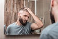 Handsome bearded dark-eyed businessman fixing his hair