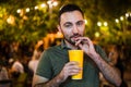 Handsome Bearded European Man Drinking coctail or beer at outdoor Street Cafe night party in park Royalty Free Stock Photo