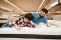 Handsome bearded father with young son is testing mattress for softness. Royalty Free Stock Photo