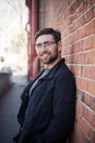 Handsome bearded glasses man in a black shirt on the background of the gray wall