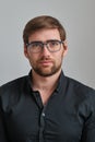 Handsome bearded glasses man in a black shirt on the background of the gray wall