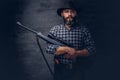 Handsome bearded hunter traveler in a fleece shirt and hat holds rifle with a sight.