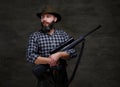 Handsome bearded hunter traveler in a fleece shirt and hat holds rifle with a sight.