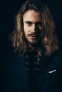 Handsome bearded long haired man holding guitar and smiling at camera