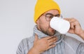 Handsome bearded male having sore throat influenza. Portrait of sick man touching his neck and drinking cup of tea, wearing Royalty Free Stock Photo