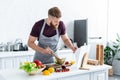 handsome bearded man in apron cooking vegetable salad Royalty Free Stock Photo