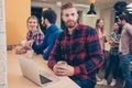 Handsome bearded man with coffee having break while his colleagues working on project Royalty Free Stock Photo