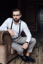 handsome bearded man in eyeglasses and suspenders sitting