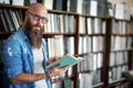 Handsome bearded man in glasses reading book in library Royalty Free Stock Photo