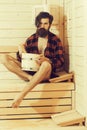 Handsome bearded man in wooden bath with bucket