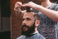 Handsome bearded man having haircut with comb and scissors