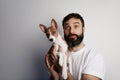 Handsome bearded man holding his basenji puppy dog in arms with love and playing with him, against a white background Royalty Free Stock Photo