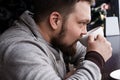 Handsome bearded man in light pullover drinking espresso