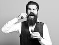 Handsome bearded man with long beard and mustache on funny face tasting glass of alcoholic shot in vintage suede leather Royalty Free Stock Photo