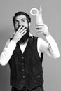 Handsome bearded man with long beard and mustache has stylish hair on surprised face holding glass of alcoholic cocktail Royalty Free Stock Photo