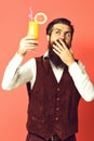 Handsome bearded man with long beard and mustache has stylish hair on surprised face holding glass of alcoholic cocktail Royalty Free Stock Photo