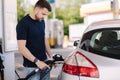Handsome bearded man refueling car at self service gas station. Petrol concept