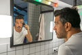 Handsome bearded man is shaving his face with trimmer machine in front of bathroom mirror Royalty Free Stock Photo