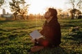 A handsome bearded man is sitting on the grass in the sun with his laptop Royalty Free Stock Photo