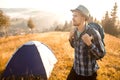 Handsome bearded man tourist exploring new places on top of mountains. Hiker man in hat with backpack happy to see sunrise