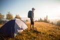 Handsome bearded man tourist exploring new places on top of mountains. Hiker man in hat with backpack happy to see sunrise