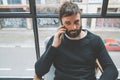 Handsome bearded man using his smartphone for making call at modern home. Blurred background. Horizontal.