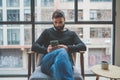 Handsome bearded man using mobile phone and drinking coffee at home. Casual relaxing and rest time concept. Blurred