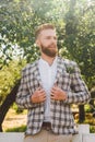 Handsome bearded man in vintage clothing. Portrait stylish groom in plaid jacket on his wedding day in the park. Rustic