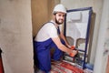 Joyful plumber installing wall-hung toilet system in bathroom.