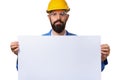 Handsome bearded man worker in protective helmet holding white advertising banner with copy space, isolated on white background Royalty Free Stock Photo