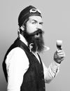 Handsome bearded pilot or aviator man with long beard and mustache on funny face holding glass of alcoholic shot in Royalty Free Stock Photo