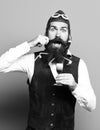 Handsome bearded pilot or aviator man with long beard and mustache on funny face holding glass of alcoholic shot in Royalty Free Stock Photo