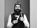 handsome bearded pilot or aviator man with long beard and mustache on funny face holding glass of alcoholic shot in Royalty Free Stock Photo