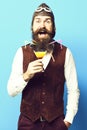 Handsome bearded pilot or aviator man with long beard and mustache on happy face holding glass of alcoholic beverage in Royalty Free Stock Photo