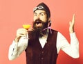 Handsome bearded pilot or aviator man with long beard and mustache on happy face holding glass of alcoholic beverage in Royalty Free Stock Photo